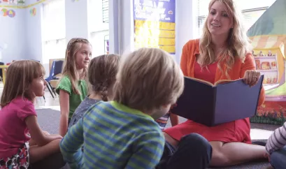 Erzieherin liest Kindern aus Buch